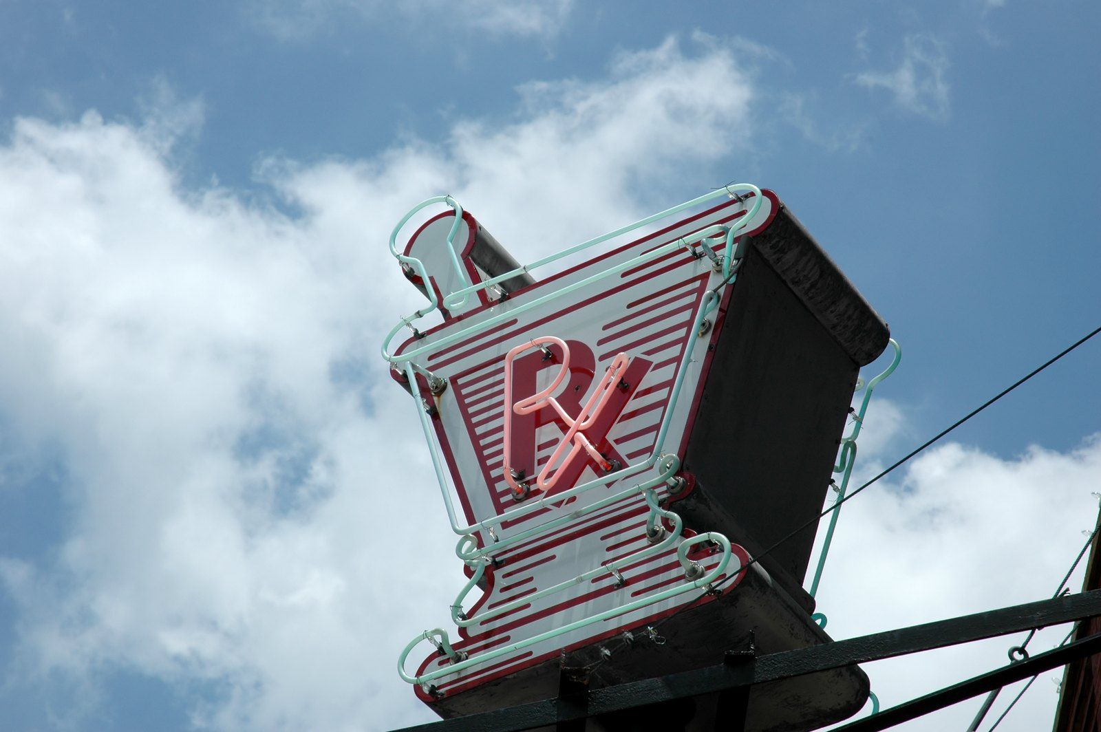 Vintage neon Rx pharmacy sign against a blue sky